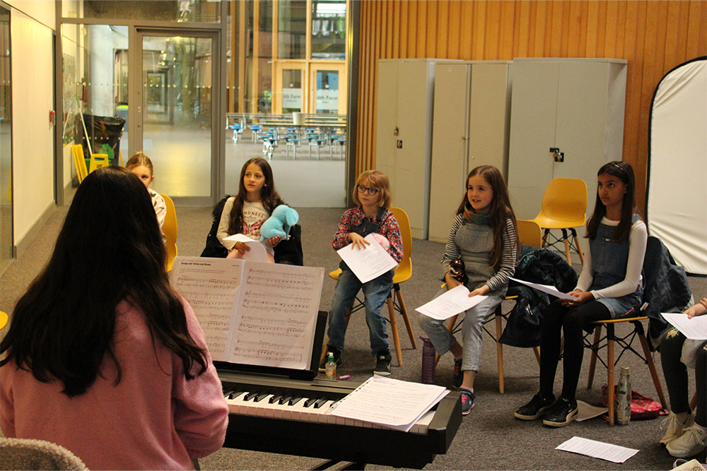 Young girls leaning to sing together in the Folkestone Junior Choir at Folkestone Music Centre