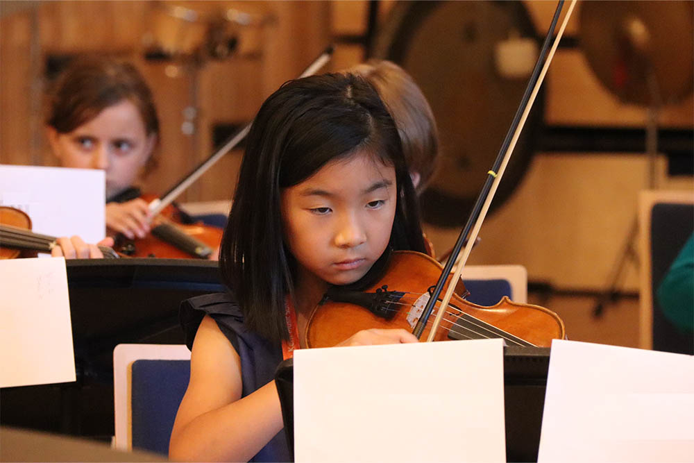 Young girl learning to play the violin with the Allegro Strings group in Gravesham