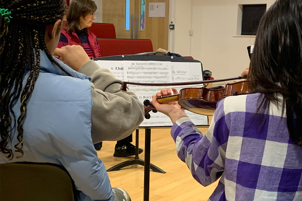 Young student musicians playing string instruments together in the Allegro Strings half term course