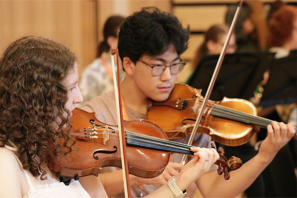 Young musicians playing violin together in Kent County Youth Orchestra string section