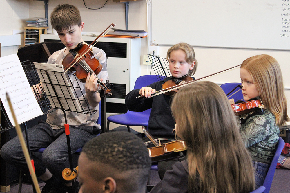 Young musicians playing string instruments together at Medway Towns Music Centre Junior Strings Group