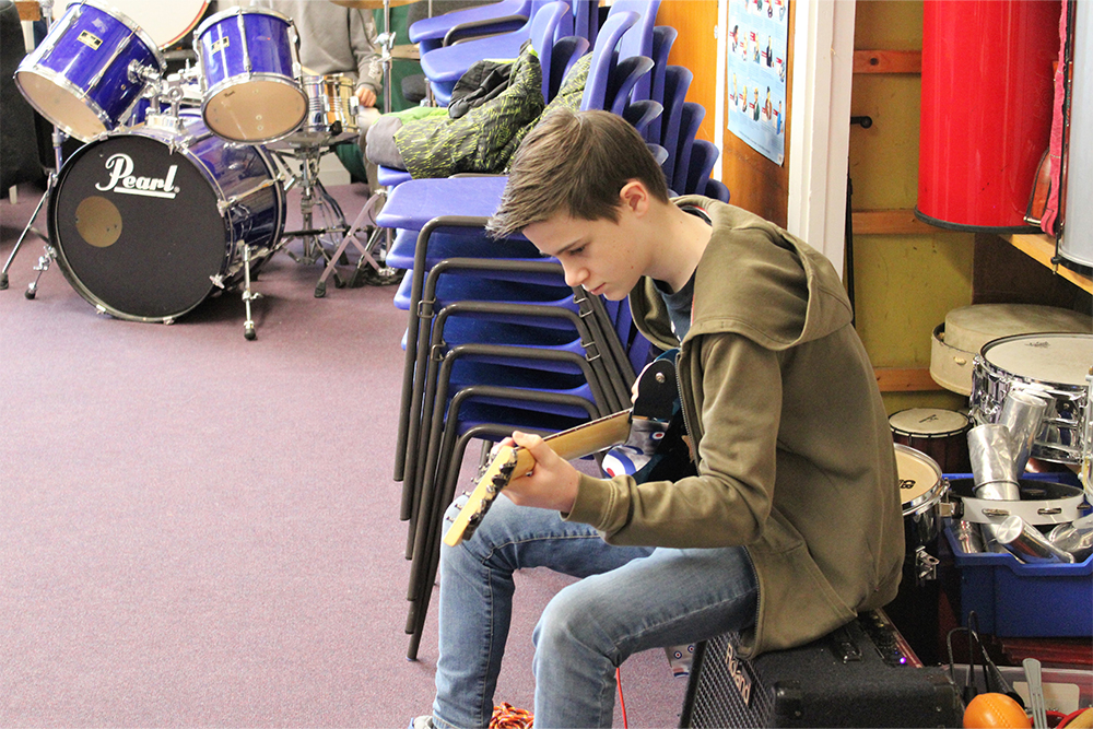 Young boy learning to play the electric guitar in Medway Towns Music Centre Rock Band,
