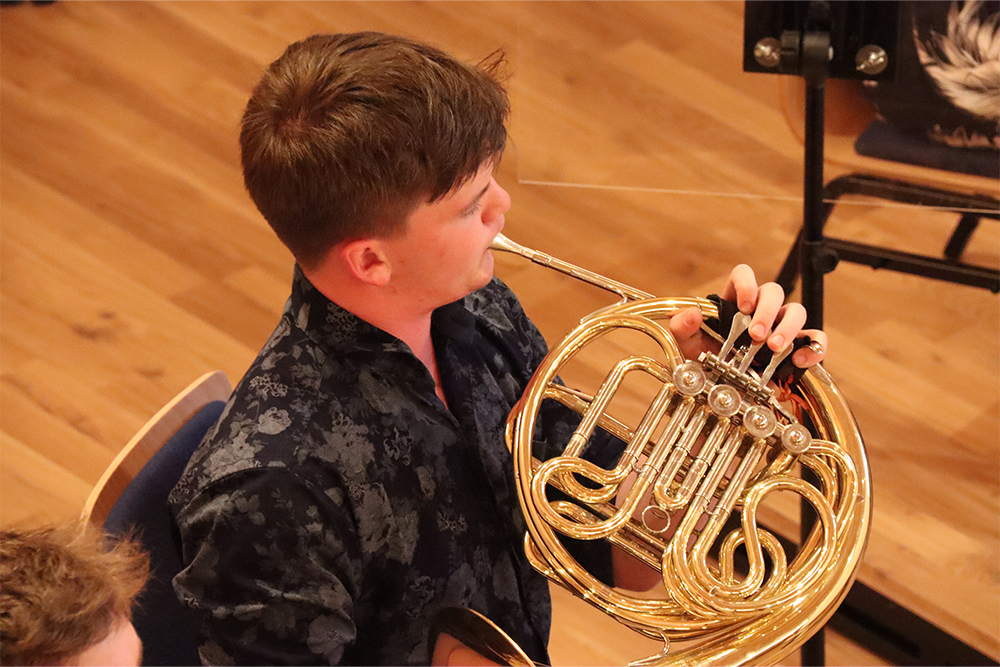 Young musician playing French Horn with West Kent Brass Band