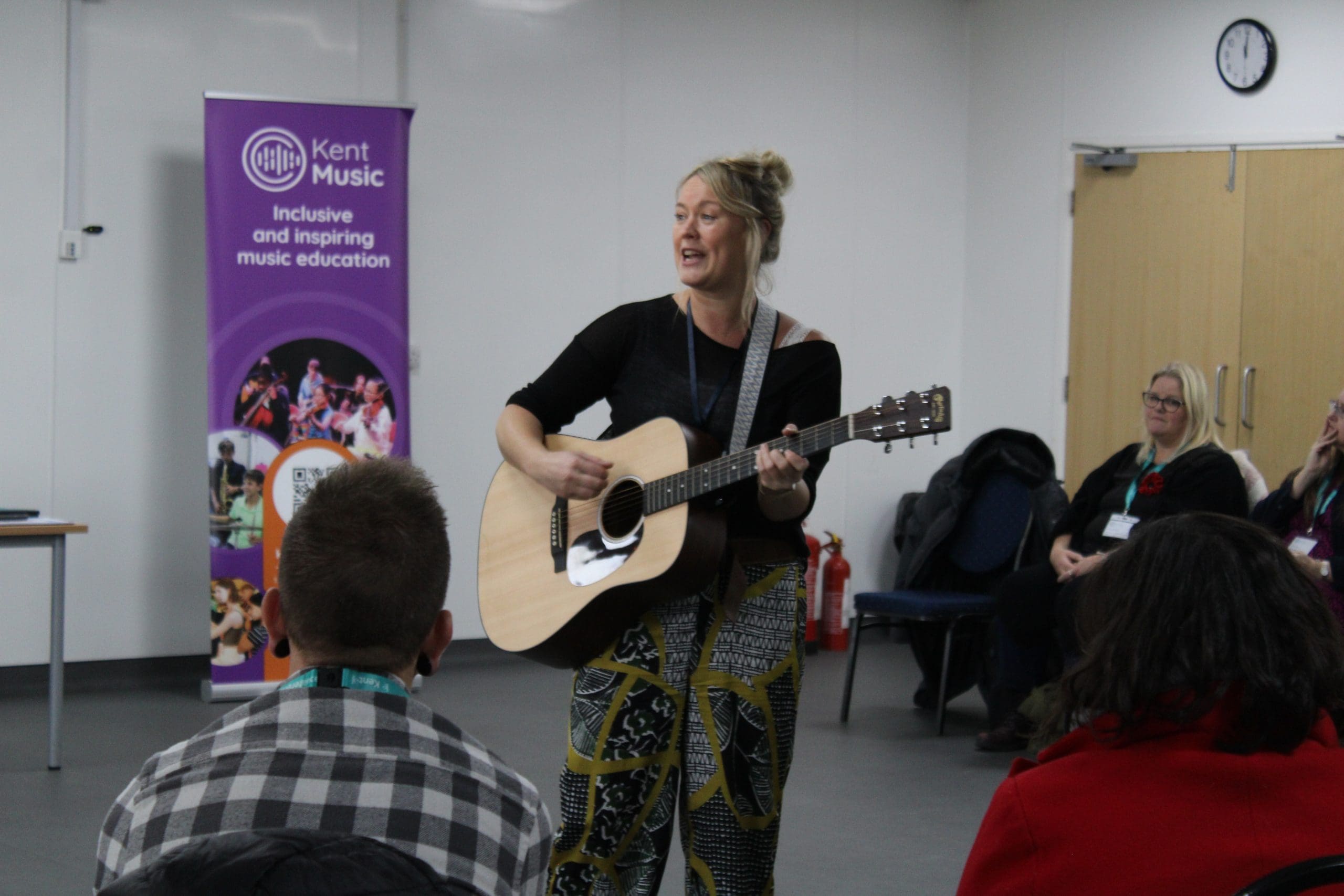 Woman delivering a workshop playing the guitar at the Kent and Medway Conference for Kent Music